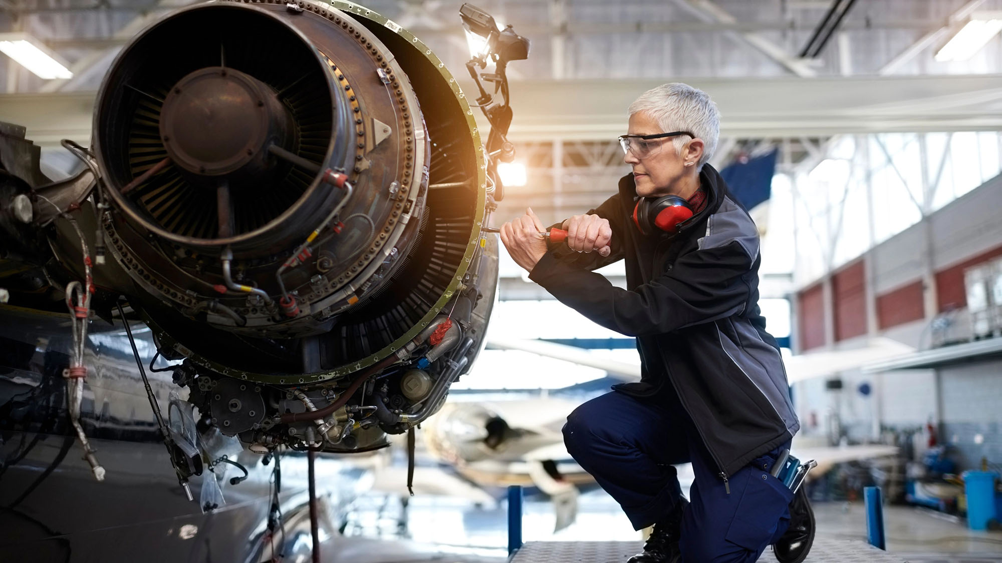 Woman engineer performing essential repairs on jet engine
